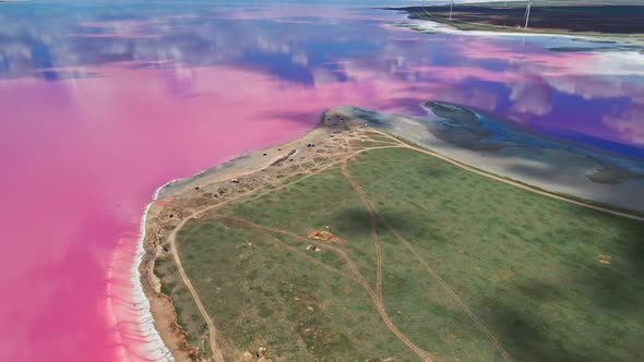 Aerial View on Beautiful Colorful Landscape with Pink Lake Coast and Wind Turbines on Background alt