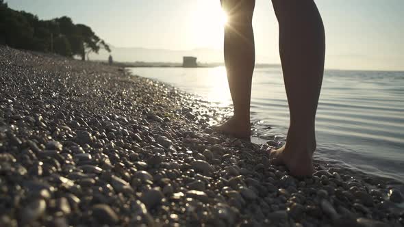 The Girl Walks Barefoot on the Beach at Dawn.