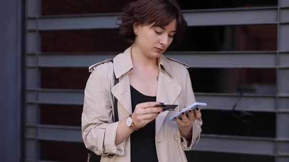 Cute Woman Chatting in Smartphone in Trench Coat