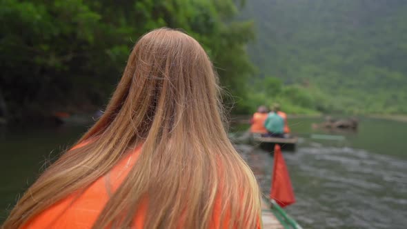 Slowmotion Shot of a Young Woman on a Boat Having a River Trip Among Spectacular Limestone Rocks in alt