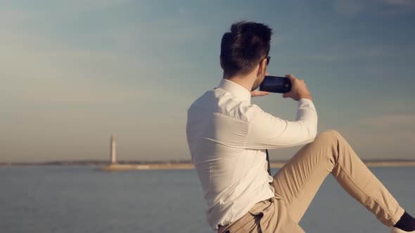 Man Hands Holding Mobile Phone And Taking Picture At Sunset. Guy Taking Photo of Sunset With Mobile alt