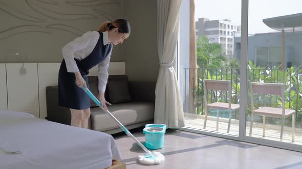 Maid was cleaning the floor with a mop in a hotel room
