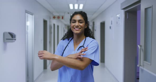 Portrait of smiling asian female doctor wearing scrubs standing in hospital corridor alt