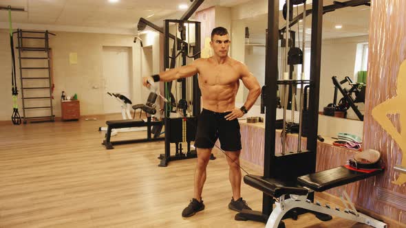 A Young Man Training in the Gym and Does a Straight Arm Lift on a Crossover Simulator for Pumping alt