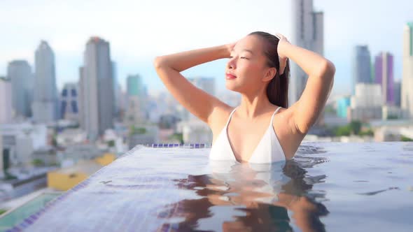 Young asian woman enjoy around outdoor swimming pool for leisure alt