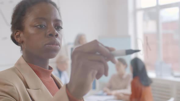 Portrait of African Businesswoman Writing on Glass Wall alt