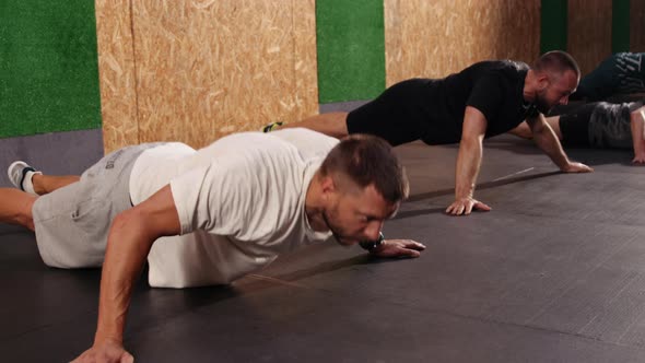 Strong Fit Athletic Men Doing Push Up Exercises in a Loft Style Industrial Gym alt