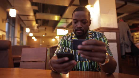 Afroamerican Man Writes Number of Credit Card Into Smartphone Online Banking