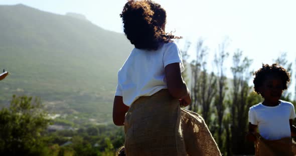 Children playing a sack race in park alt