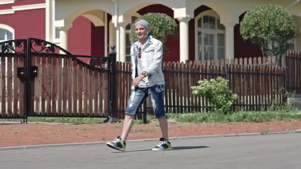 Active Senior Hipster Trying to Catch his Skateboard alt