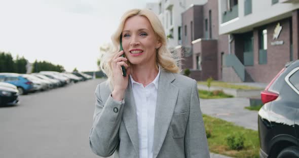 Businesswoman Walking on Street in City and Speaking on Mobile Phone Onthe go to Office Outdoors. alt