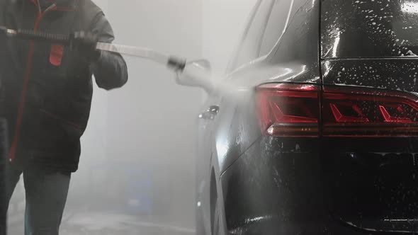 Make Worker Washing Black Car Arches Under High Pressure Water After Foam Application alt