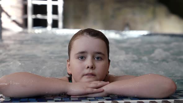 Little Girl in Waterpark Lying in Pool with Bubbling Water alt