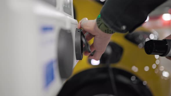 Slow Motion person charging an electric vehicle in underground car park alt