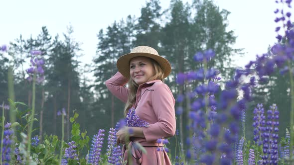 Attractive Woman in Dress Hat Stands in Field of Lupins Looks Up, Feminine Mysterious Girl alt