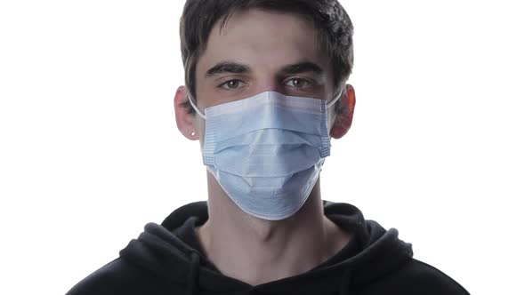 Portrait of a Young Man Taking Off His Medical Mask and Smiling on a White Background, Isolate Covid