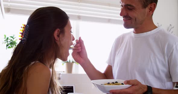 Young man feeding his woman in the kitchen at home 4k