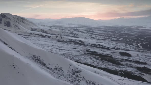Breathtaking Aerial View of White Snow on Black Mountain Rocks at Sunrise alt