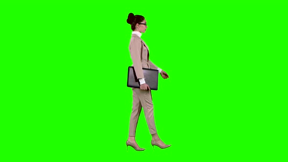 Girl Is Going To a Meeting with a Laptop in Her Hands. Green Screen. Side View. Slow Motion alt