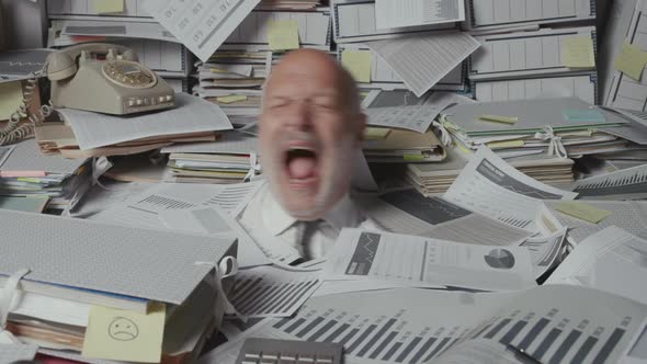 Stressed angry businessman overloaded with paperwork