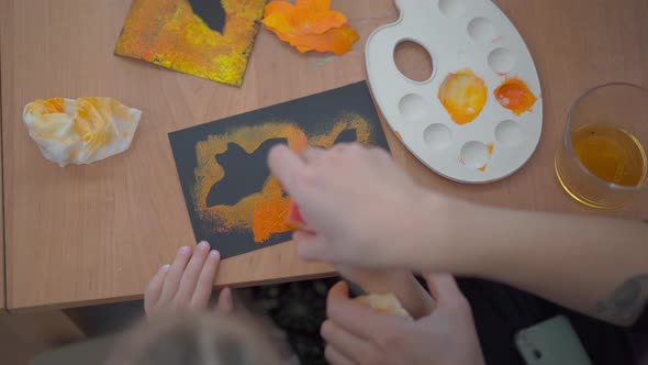 Little Girl Dressed Halloween Carnival Costume with Her Mother Sitting on the Table Drawing Handmade alt