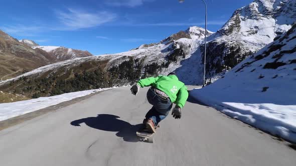 A man downhill skateboarding on a mountain road alt