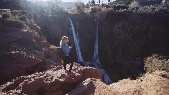 Tourist Standing On Cliff Edge Next To Ouzoud Falls alt