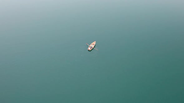 Aerial View Lone Wooden Boat in the Middle of Water Surface of a Mountain Lake alt