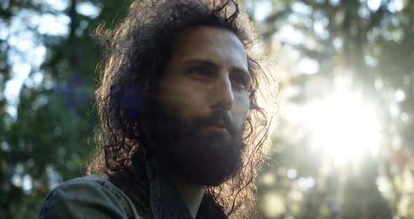 Closeup of a Handsome Bearded Charismatic Man with Curly Hair at Sunset Speaks To the Interlocutor alt
