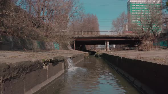 The River Flowing in a Concrete Reservoir in the City alt