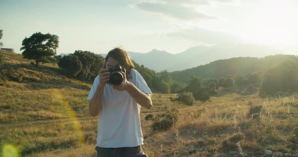 Creative Man Using Digital Camera to Make Photo on Summer Mountain Journey alt