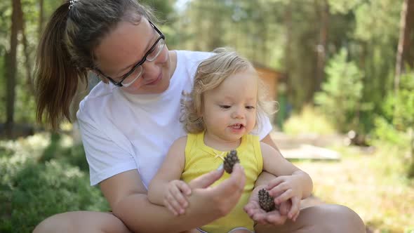 Little Cute Baby Toddler Girl Blonde with Curls on Mother's Arms alt