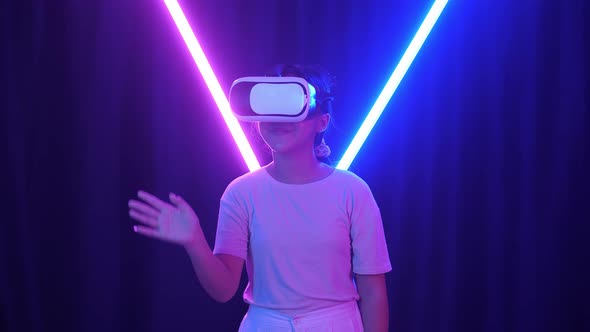 Excited Asian Young Girl Using Virtual Reality Headset And Use Hand Slide With Neon Light alt
