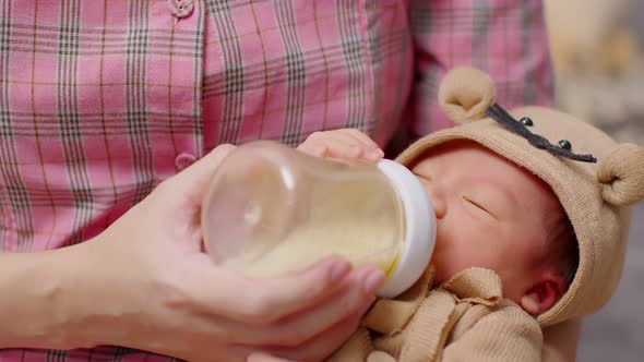 Newborn baby drinking milk from bottle on mom arms, Stock Footage