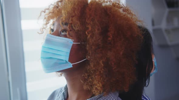 Close Up. African American and Asian Women with Medical Mask Standing Back To Back in Front of the alt