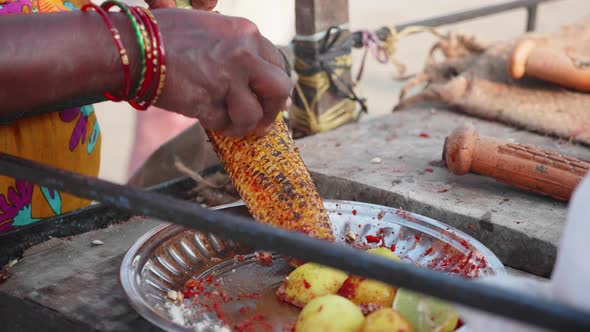 Street Vendor Is Rubbing a Roasted Sweet Corn Cob with Lemon and Spices.