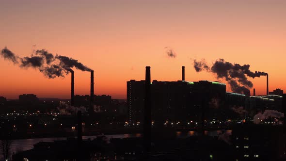 Smoke From Pipes in the City Against the Red Sky. Pipes and Houses in Silhouette. Lots of Pipes