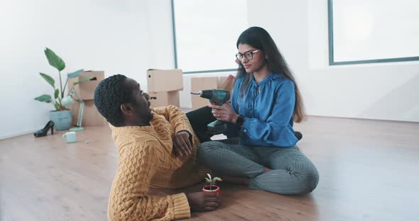 Young couple moving into new home sitting on the floor alt