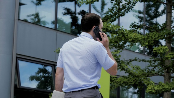 Urban Business Man Talking on Smart Phone Walking. alt