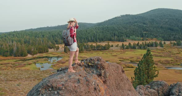 Woman Tourist on the Rock Enjoying Cinematic Forest View and Scenic Landscapes alt