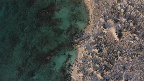 Aerial Top Down Flyover Shot of Deserted Beach in Cyprus. Flying at Sunset Above Coast alt