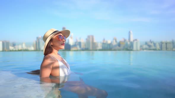 Young asian woman enjoy around outdoor swimming pool for leisure alt