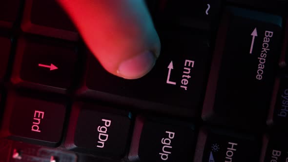 The computer keyboard, which is shot close to the abstract lights, is pressed at the enter