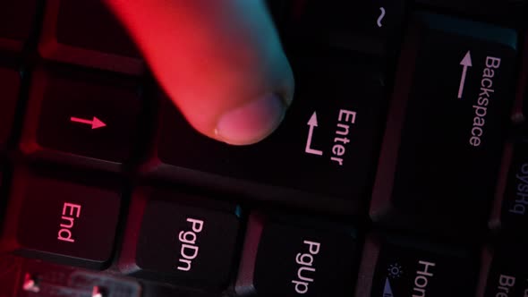The computer keyboard, which is shot close to the abstract lights, is pressed at the enter alt