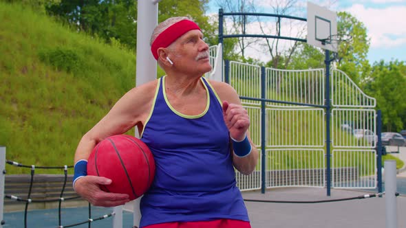 Senior Man Grandfather After Sport Basketball Training Sitting Listening Music on Playground Court alt