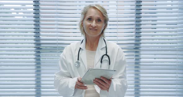 Middle aged female doctor using tablet and talking to camera 4k alt