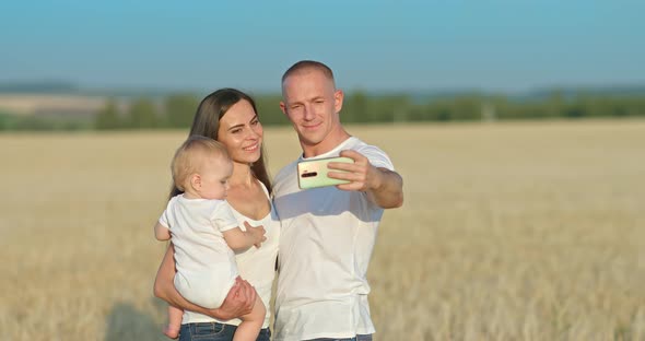 Young Family Takes a Selfie on a Smartphone in a Wheat Field a Photo Shoot alt