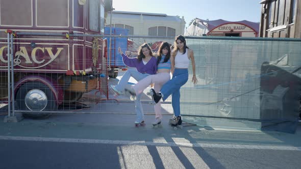 Three Smiling Girls By Metal Fence Lift Their Roller Skates Pushin alt