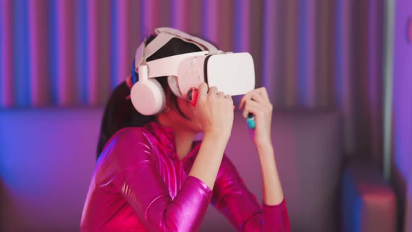 Young asian woman is using virtual reality headset. Neon light studio portrait alt