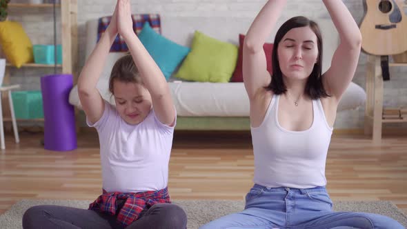 Close Up Mother and Daughter Doing Yoga Sitting on the Floor alt